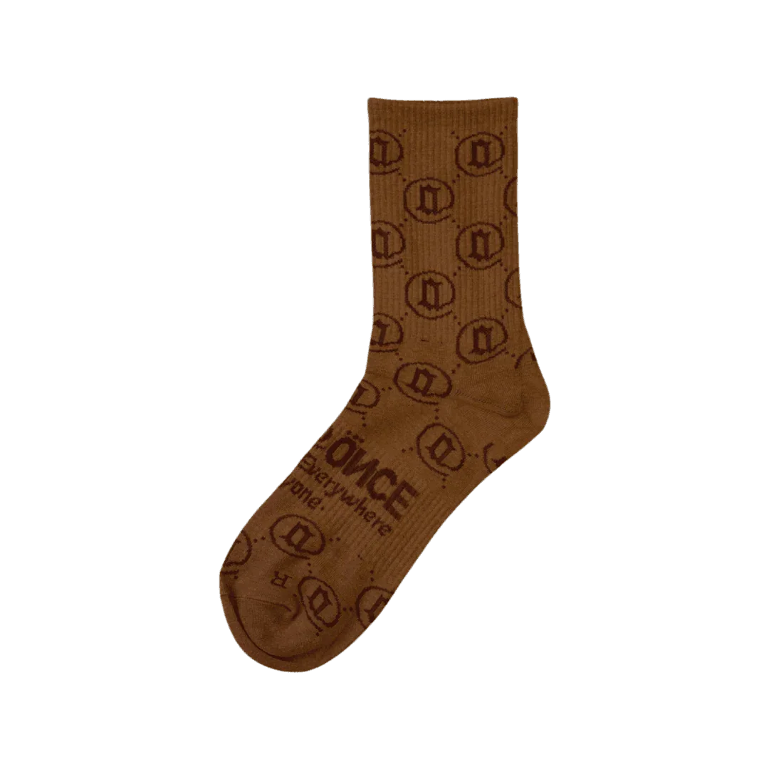 Brown monogram crew sock with geometric patterns and text, isolated on blue background