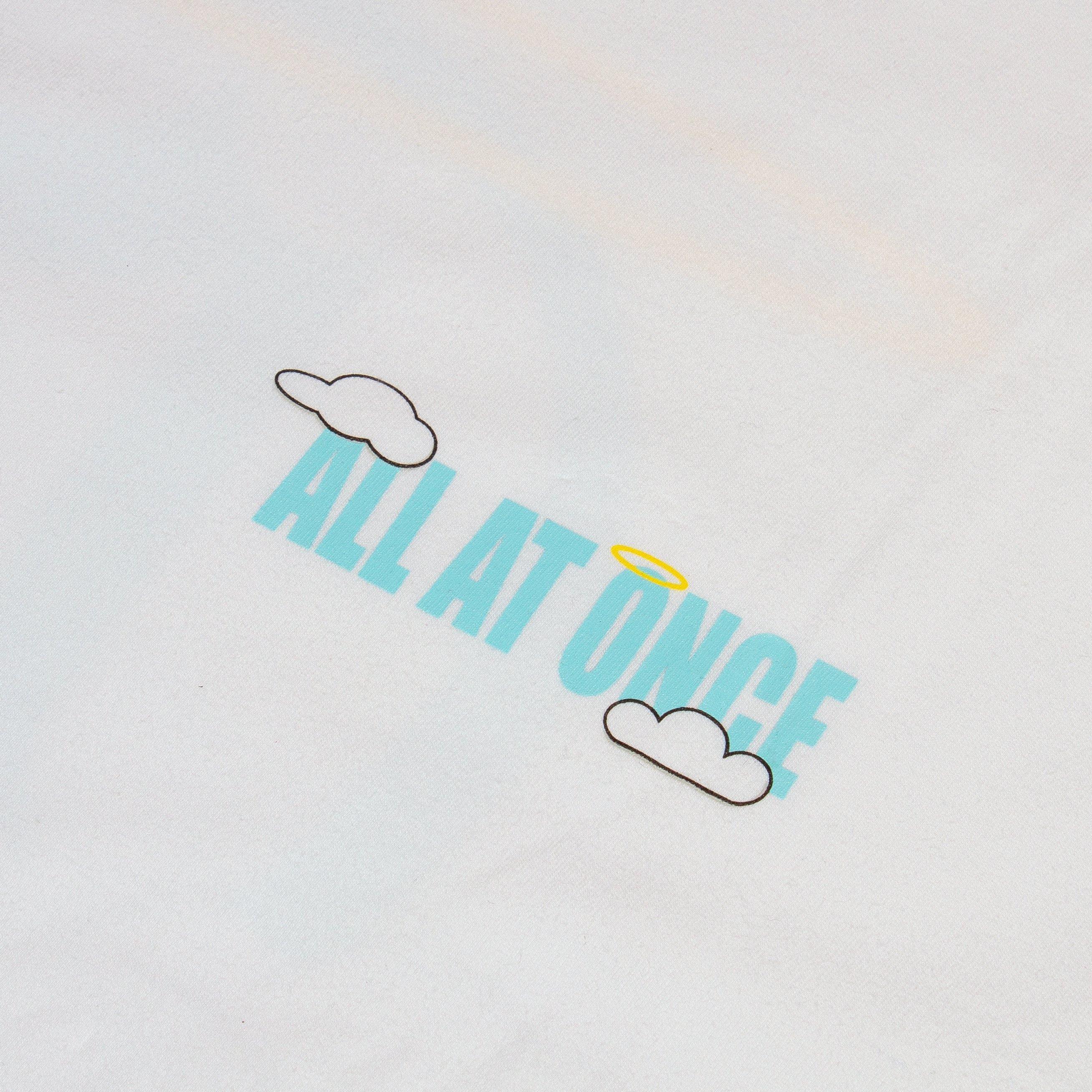 White t-shirt with blue 'ALL AT ONCE' text, clouds, and yellow halo graphic print